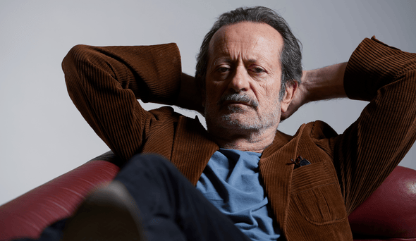 Foto dell'attore Rocco Papaleo seduto rilassato su un divano